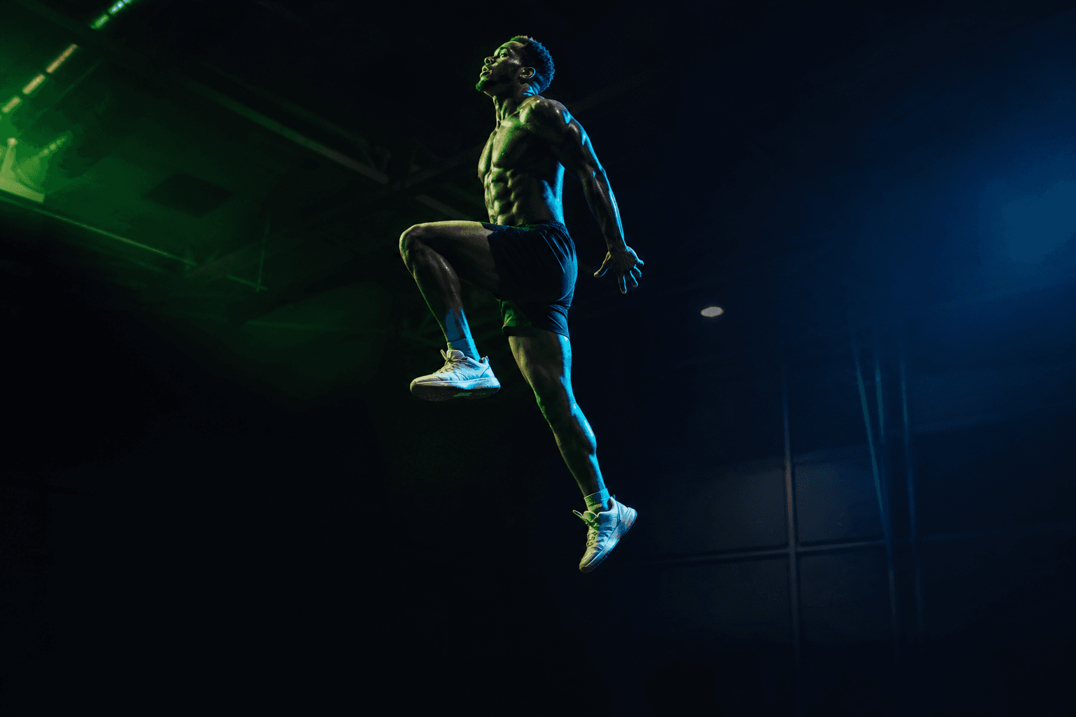 Athlete exploding upward from a deep jump in a dark gym with lime and cyan rim lighting