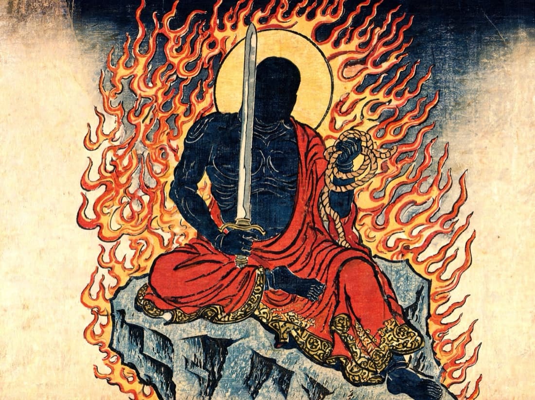Fudō Myōō, the Immovable Wisdom King, seated on a rock throne and wreathed in flame, an upright sword in one hand and a coiled rope in the other.